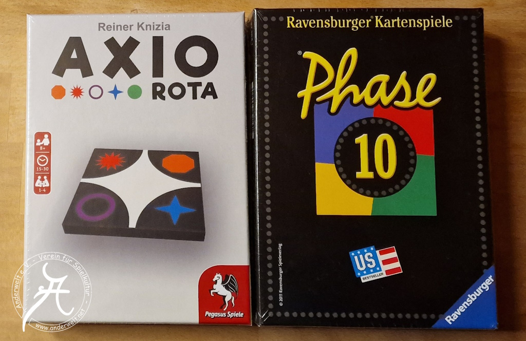Das Bild zeigt die nebeneinanderliegenden Spieleschachteln in Shrinkwrap-Verpackung. Darauf sind ein Spielplättchen von Axio Rota bzw. ein in vier Farbfelder unterteiltes Quadrat bei Phase 10 abgebildet.