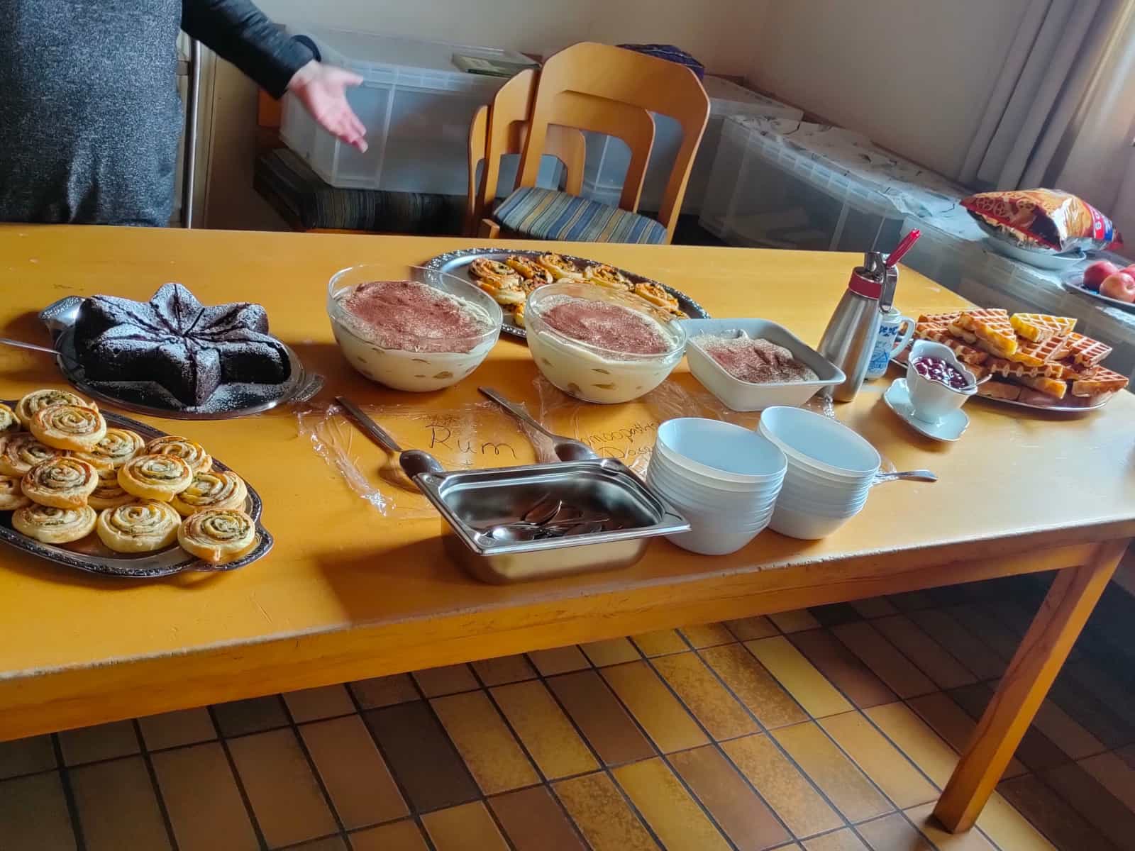 Gedeckte Tafel mit Tiramisu, Schokoladenkuchen, frischen Waffeln und herzhaften Käse-Schnecken.