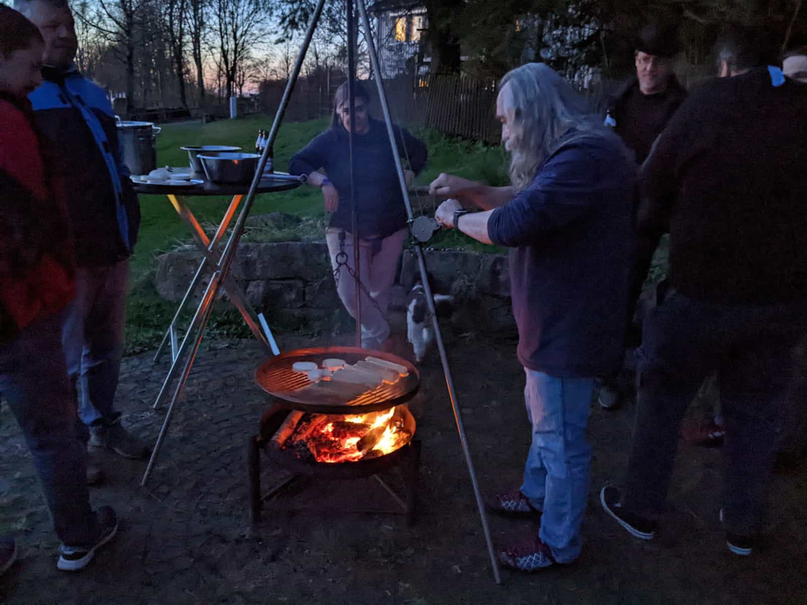 Hungrige Meute versammelt sich um den mit Würstchen, Fleisch und Käse belegten Schwenkgrill.