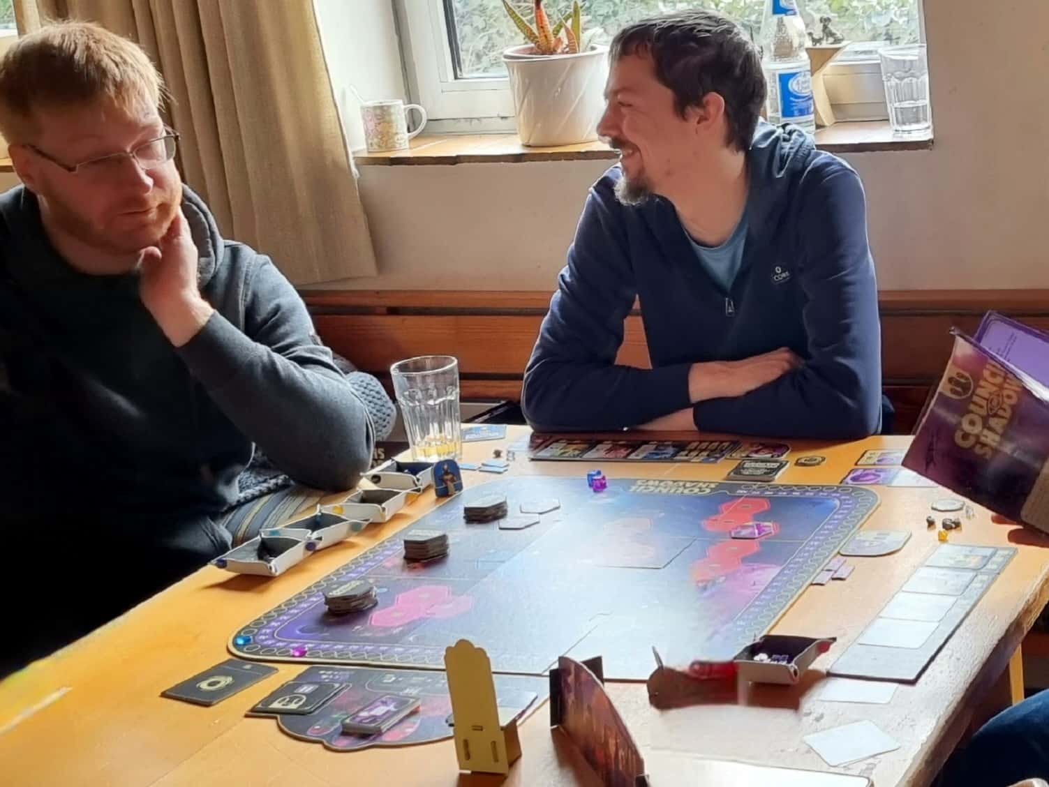 Zwei fröhliche Spieler bei einer Partie Council of Shadows.