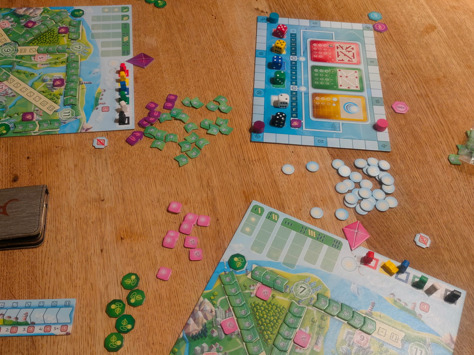 Eine Partie Powerline. Zu sehen ist der gemeinsame Spielplan mit den farbigen 6-seitigen Würfeln in fester Reihenfolge und den unterschiedlichen Wertungen. Daneben sind zwei der persönlichen Spielbretter mit den zu vollendenden Stromleitungen auf einer Karte abgebildet.