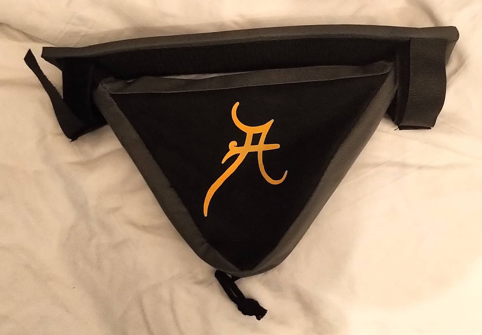 Kleine dreieckige schwarze Fahrradtasche für Werkzeug oder Schlüssel mit dem orangefarbenen Anderwelt-A darauf.