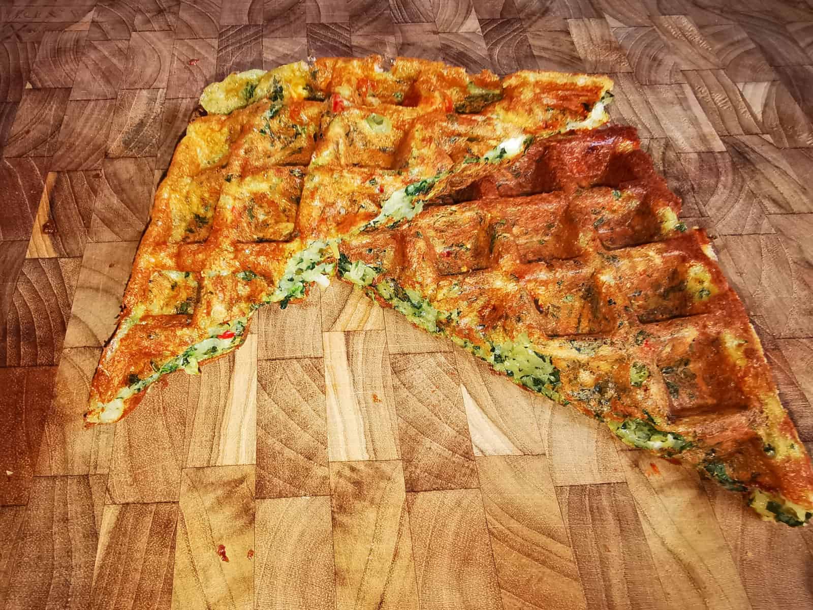 Geteilte Kartoffel-Spinal-Waffel auf einem Holzbrett präsentiert.