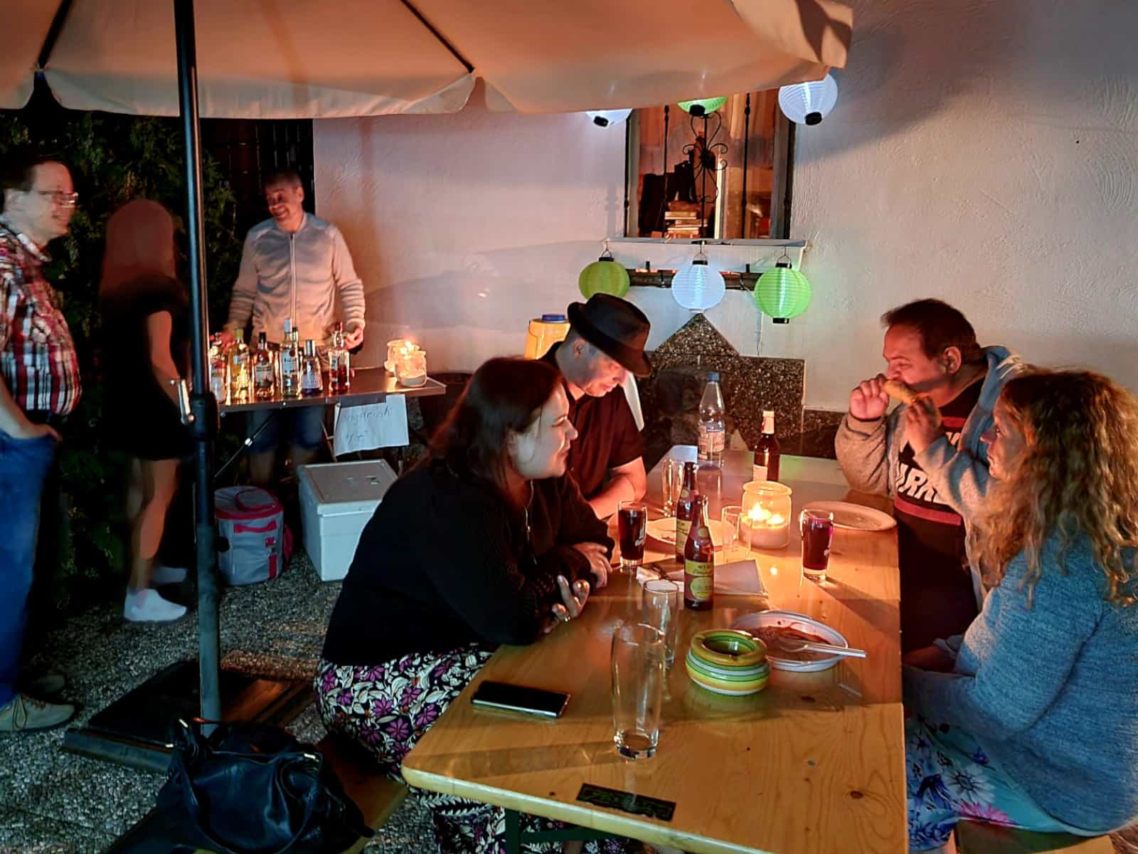 Besucher genießen Essen und Cocktails im Kerzenschein.